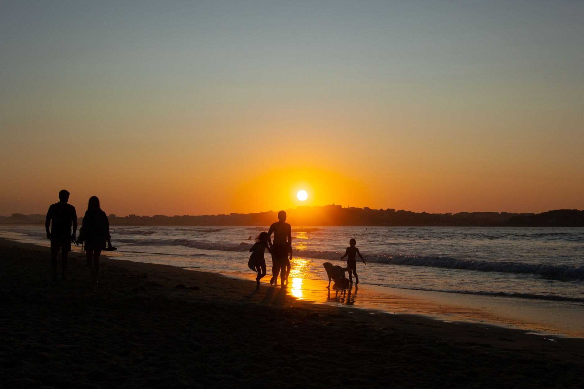 Família a caminhar numa praia de Marbella com águas calmas